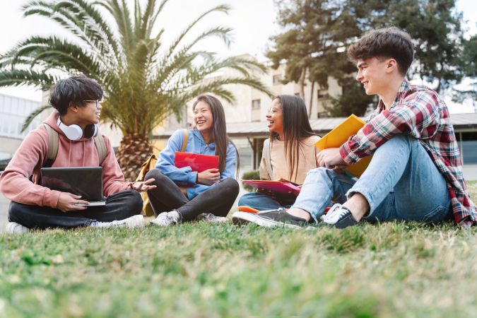 Students smile and laugh together while sitting outside