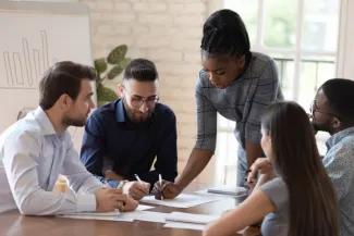 5 educators seated at a table and working on a project