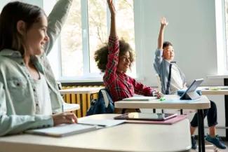 Three students with hands raised